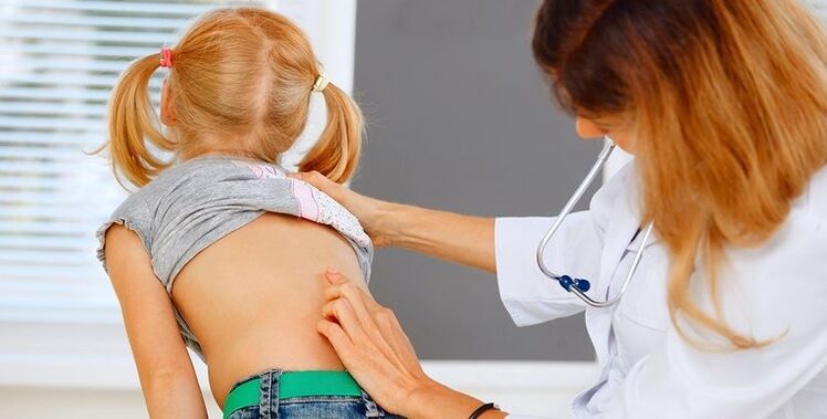 Doctor examining the back of a child with low back pain